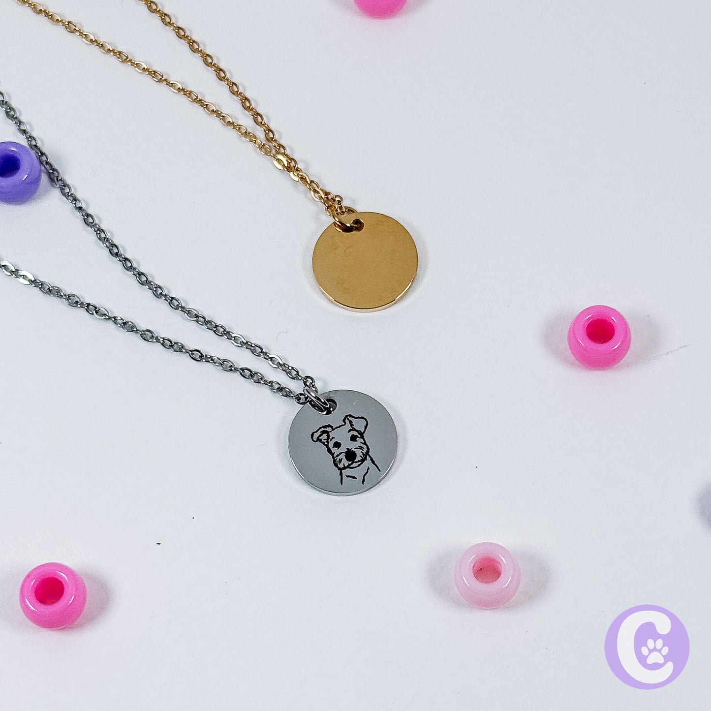 Two necklaces with round pendants on a white background with pink beads.