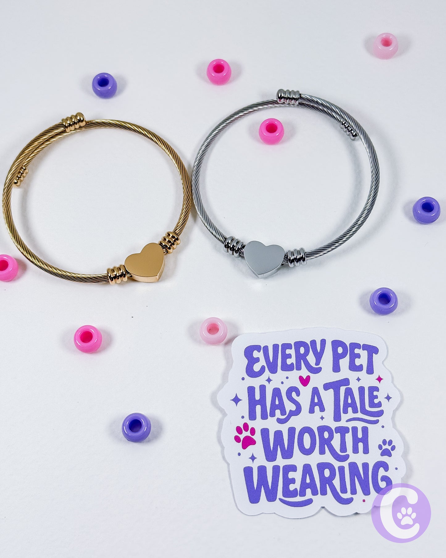 Two bracelets with heart-shaped clasps on a white background with decorative beads and a sticker reading 'Every pet has a tale worth wearing'.