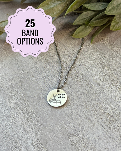 Necklace with a round pendant on a textured surface with green leaves.