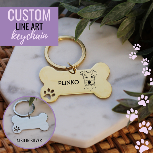 Gold bone-shaped keychain with engraved dog illustration and 'Plinko' text on a marble surface.
