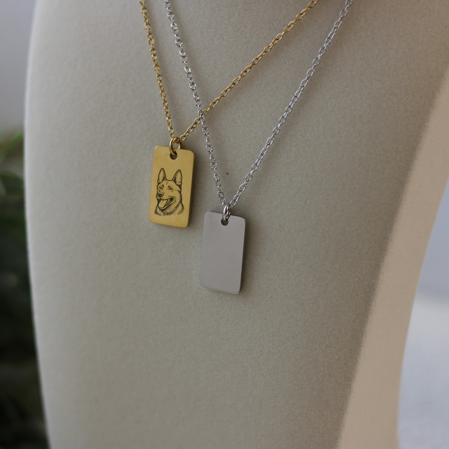 Two necklaces with rectangular pendants on a mannequin bust.