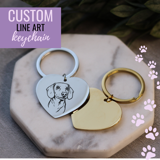 Heart-shaped keychains with a dog illustration on a marble surface with paw prints.