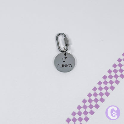 Round metallic keychain with 'Plinko' branding on a light gray background