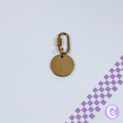 Gold keychain with a round tag on a light purple background