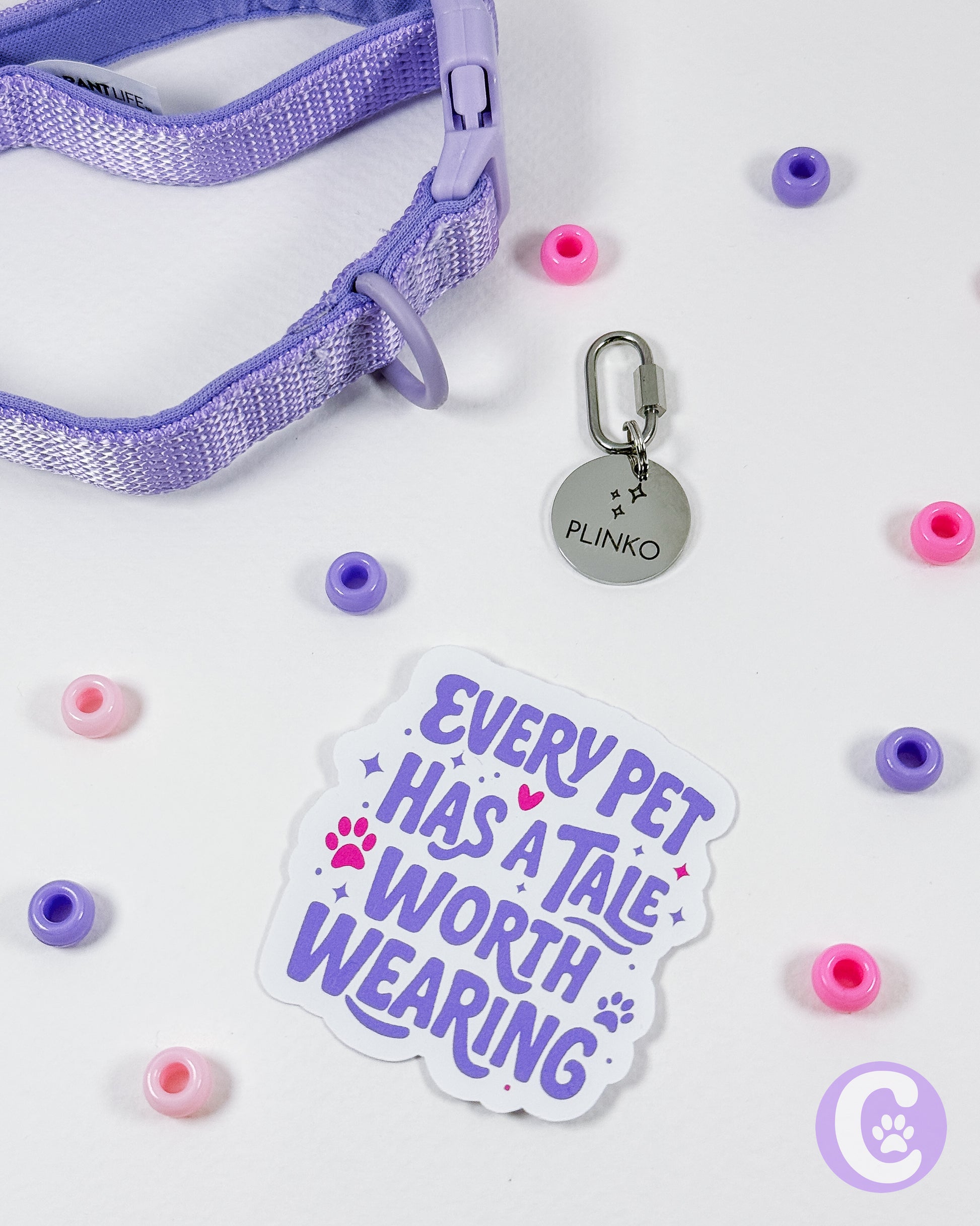 Purple pet collar with a tag, pink and purple beads, and a 'Every Pet Has a Tale Worth Wearing' sticker on a white background.