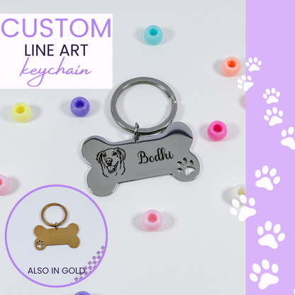 A silver bone-shaped keychain with engraved custom line art of a dog and the name 'Bodhi', shown on a white background with colorful round beads and a purple side panel with paw prints. Text reads 'CUSTOM LINE ART keychain' and a circular inset shows a gold version labeled 'ALSO IN GOLD'.