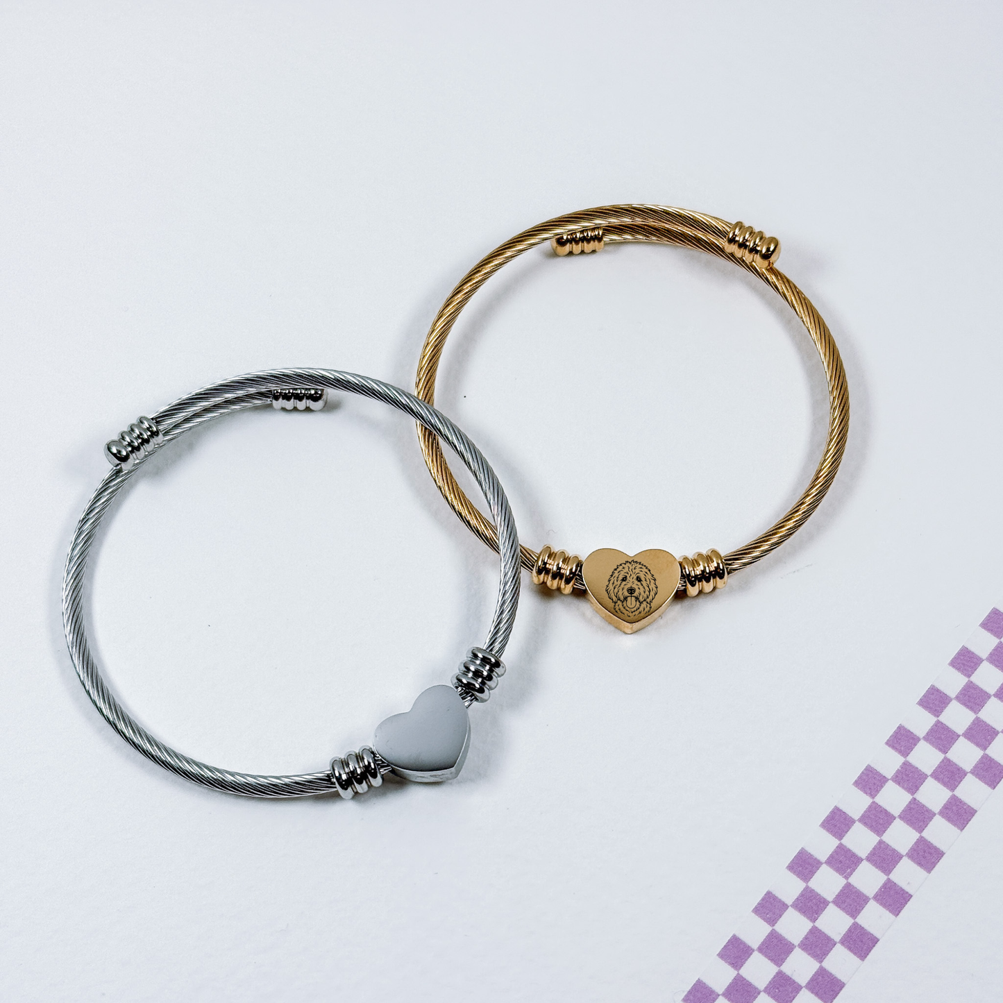 Two bracelets with heart-shaped charms on a light purple background