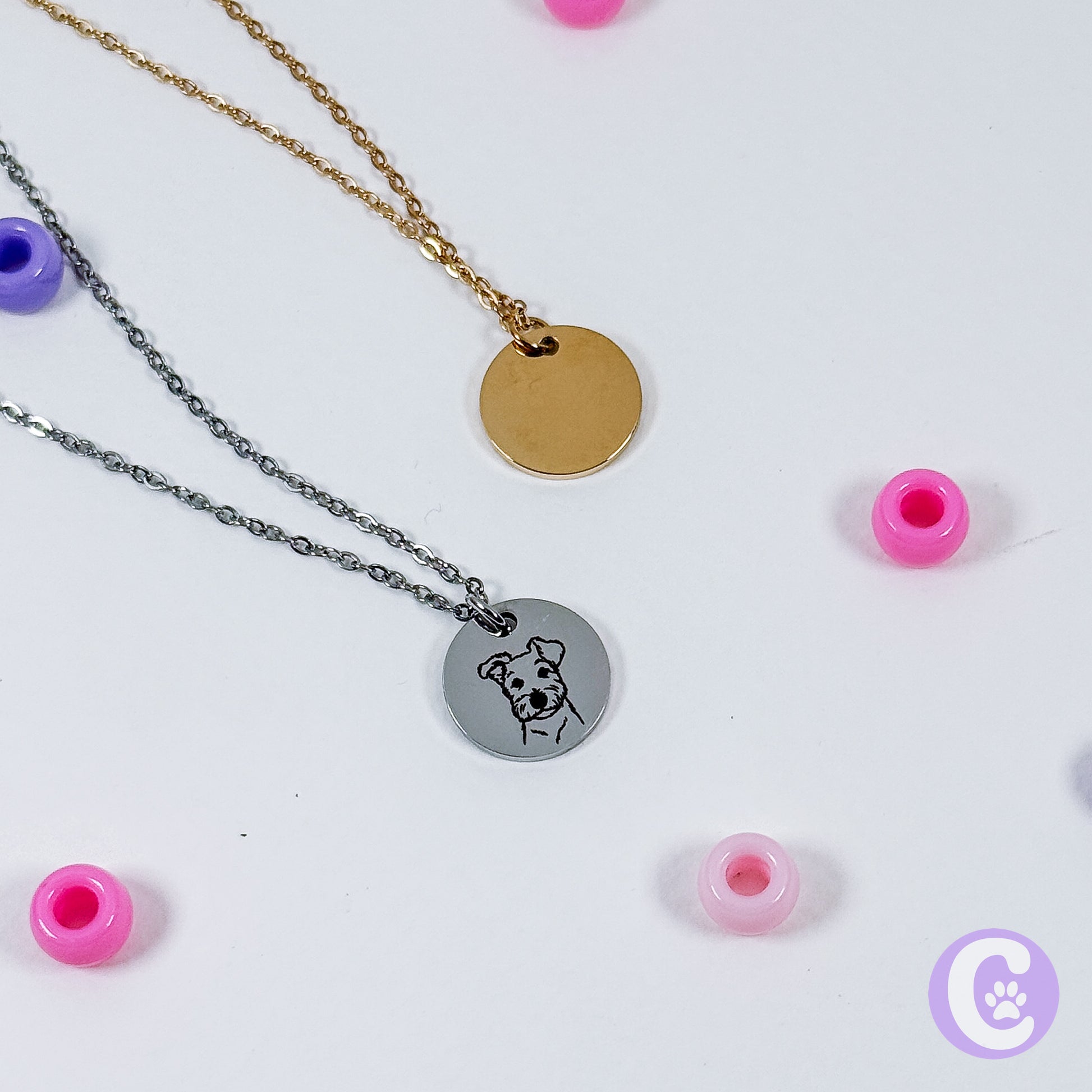 Two necklaces with round pendants on a white background with pink beads.