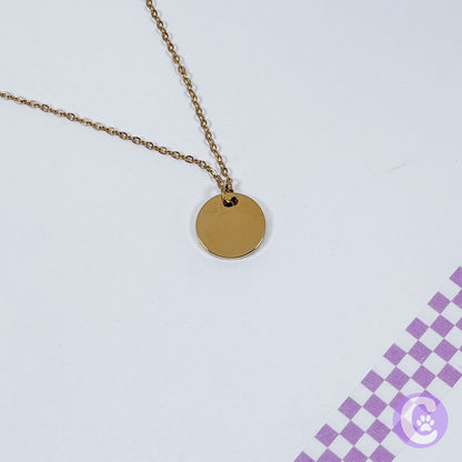 Gold necklace with a round pendant on a light gray background