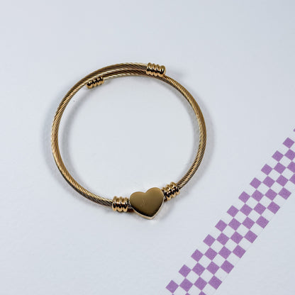 Gold bracelet with a heart-shaped clasp on a light gray background