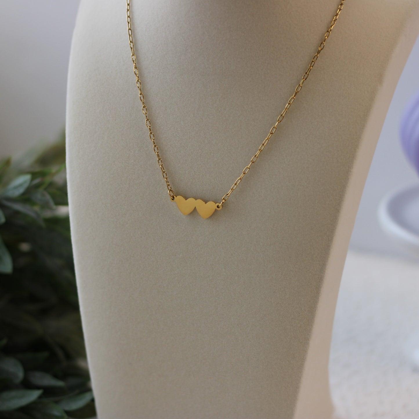 Gold necklace with heart pendants on a mannequin bust.