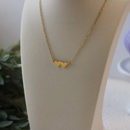 Gold necklace with heart pendants on a mannequin bust.