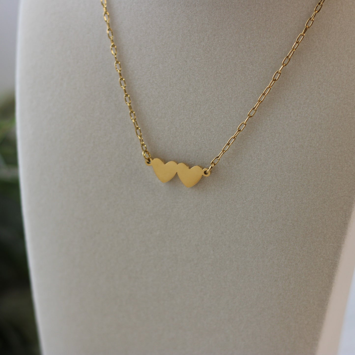 Gold necklace with heart pendants on a mannequin bust.