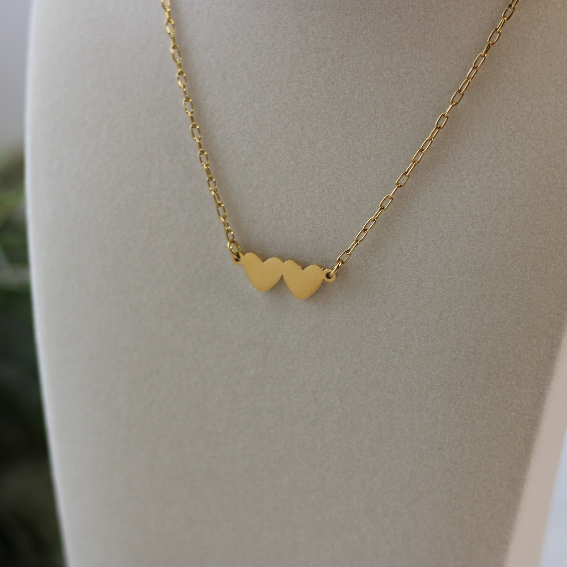 Gold necklace with heart pendants on a mannequin bust.