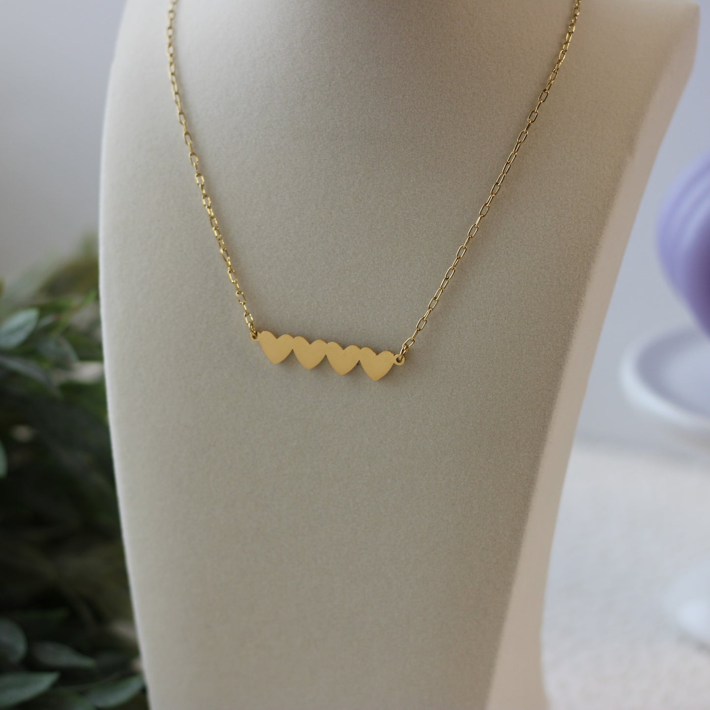 Gold heart-shaped necklace on a mannequin with a blurred background