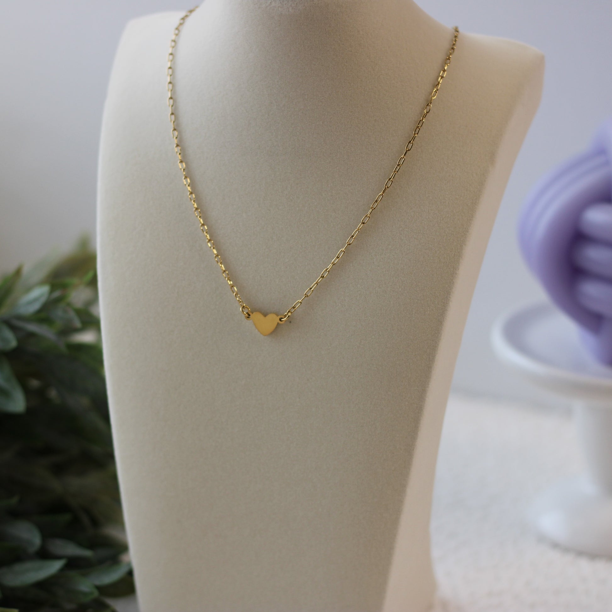 Gold heart-shaped pendant necklace on a mannequin bust with a blurred background