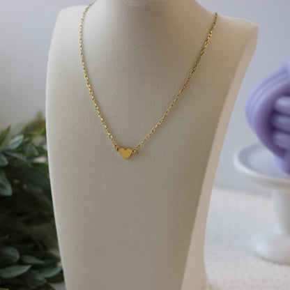 Gold heart-shaped pendant necklace on a mannequin bust with a blurred background