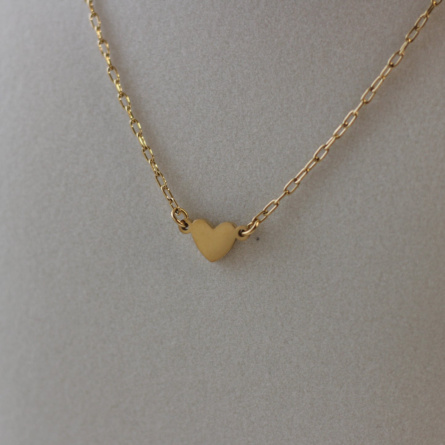 Gold heart-shaped pendant necklace on a plain background
