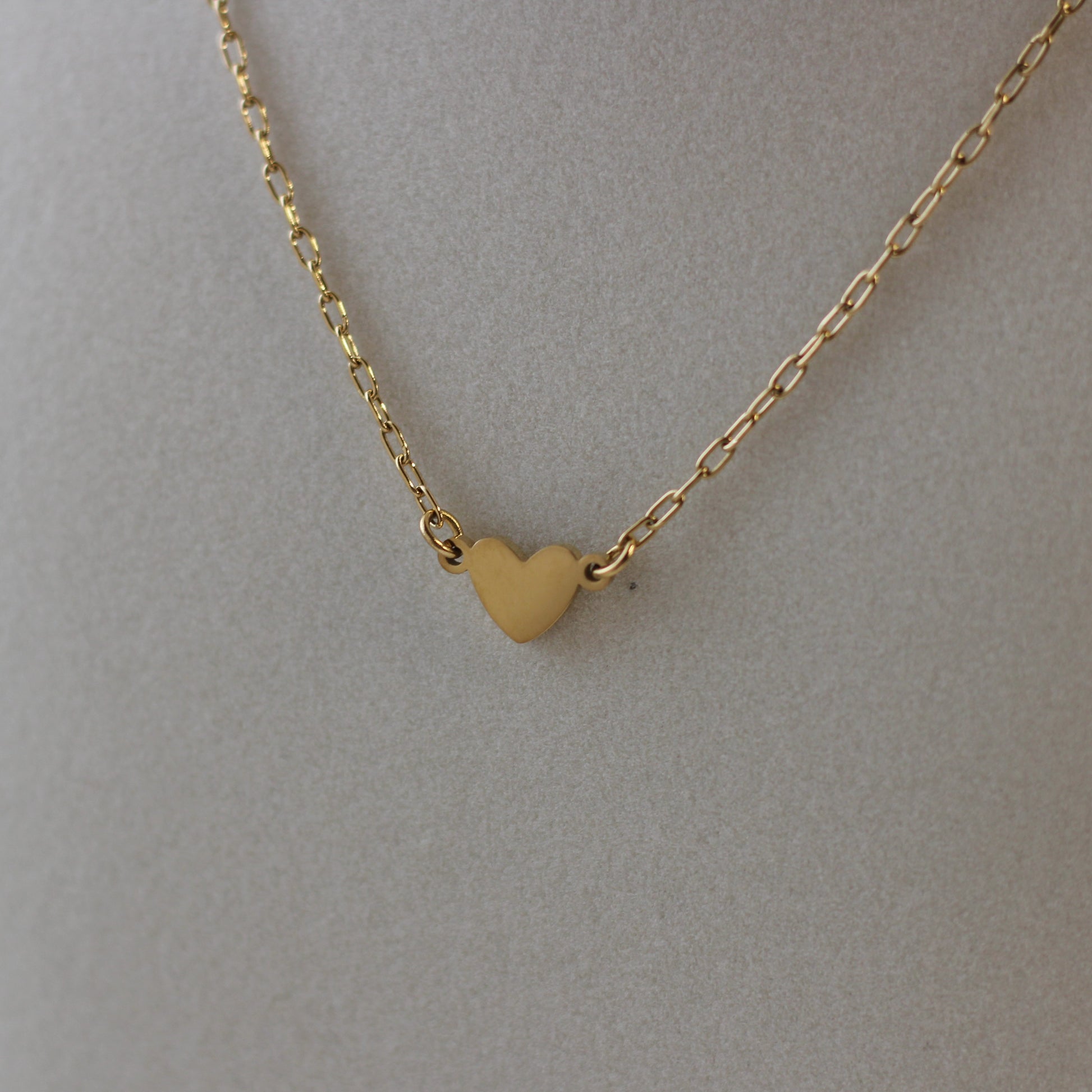 Gold heart-shaped pendant necklace on a plain background