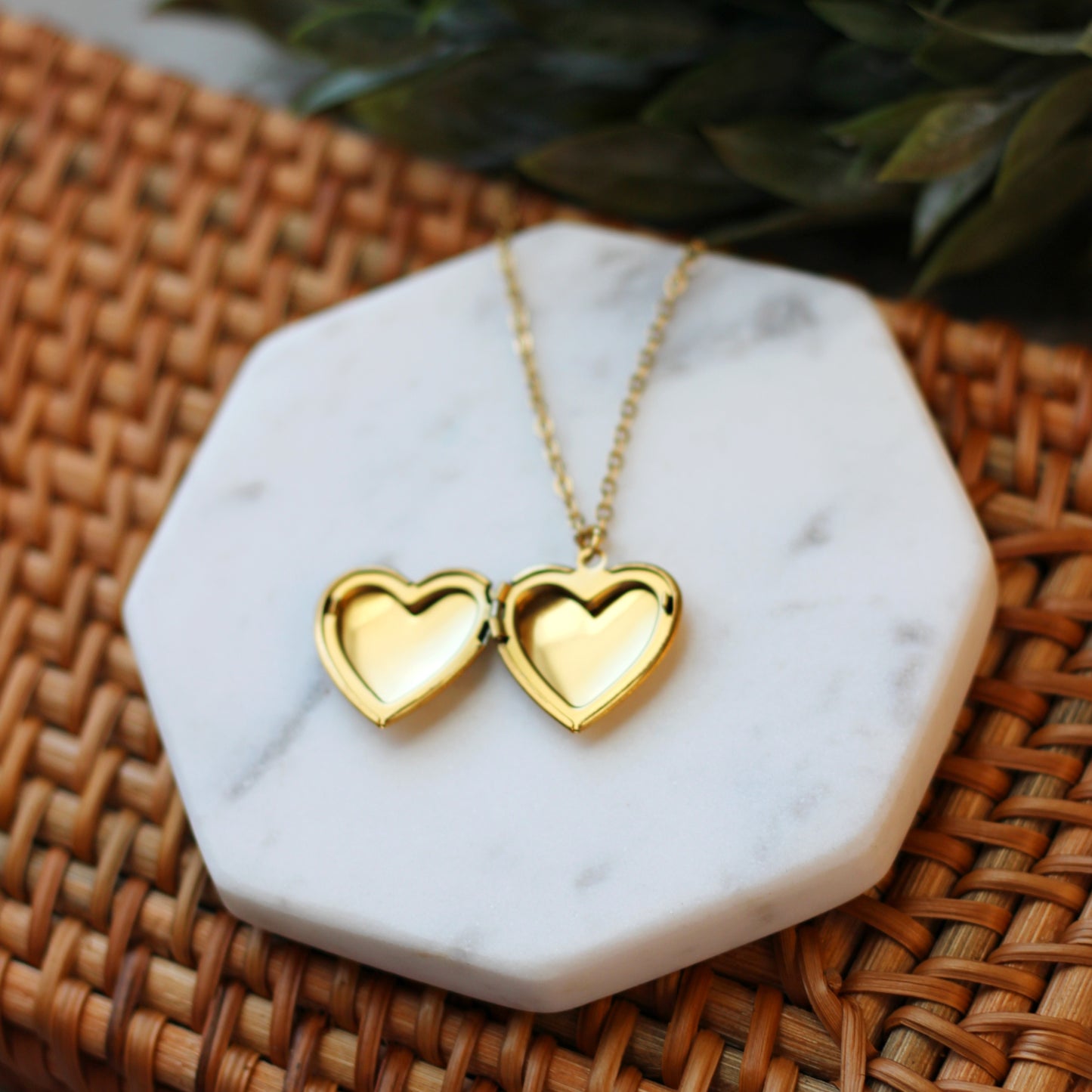 Gold heart-shaped necklace on a marble stand with a woven surface background