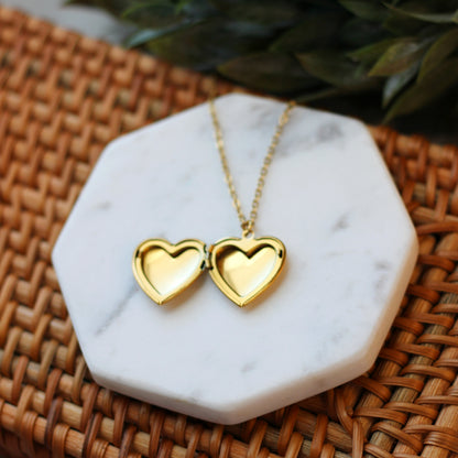 Gold heart-shaped necklace on a marble stand with a woven surface background