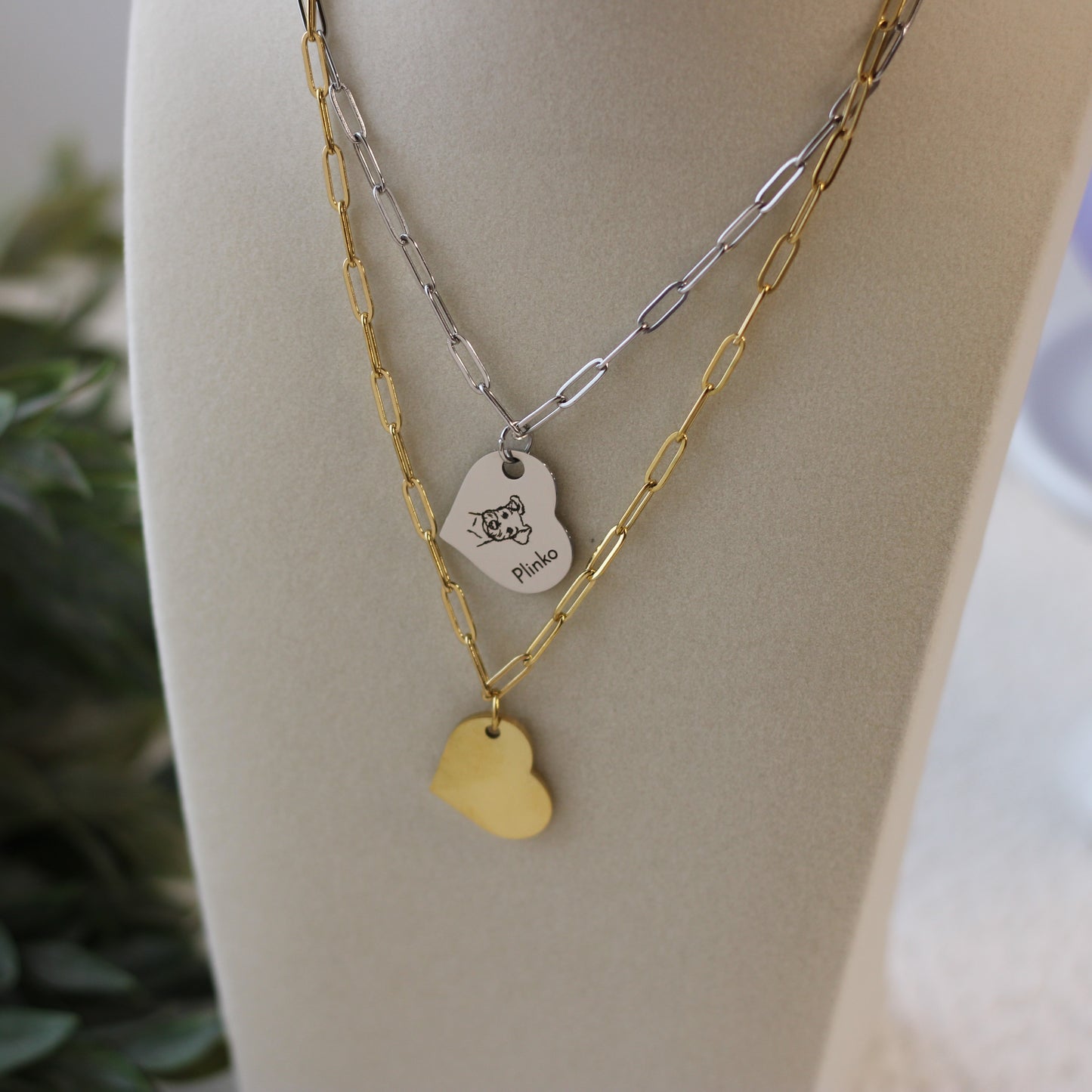 Two necklaces with heart-shaped pendants on a mannequin bust.
