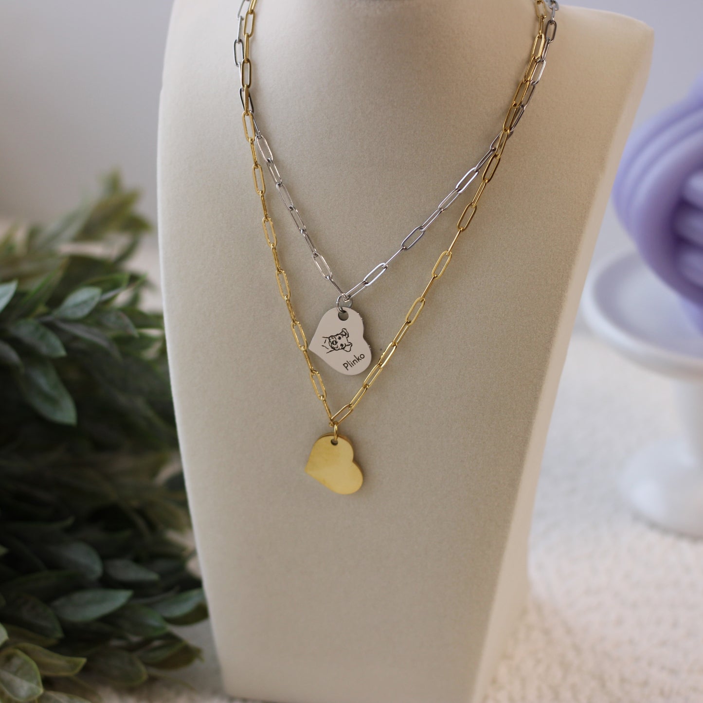 Two necklaces with heart-shaped pendants on a mannequin bust with a blurred background