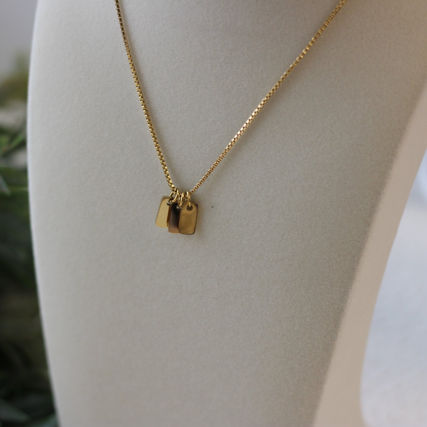 Gold necklace with a pendant on a mannequin bust.