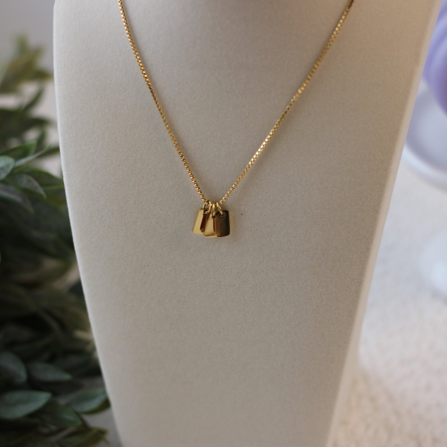 Gold necklace with a pendant on a mannequin bust.