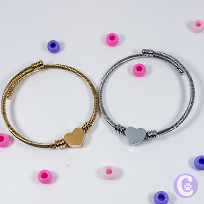 Two bracelets with heart-shaped ends on a white background with scattered beads.