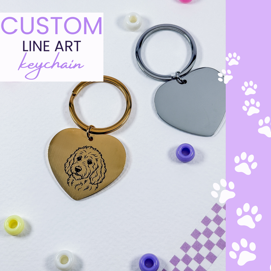 Two heart-shaped metal keychains with key rings on a white background, one engraved with a dog portrait and one plain. Purple paw-print graphics and a text label reading 'CUSTOM LINE ART keychain' appear in the corners.