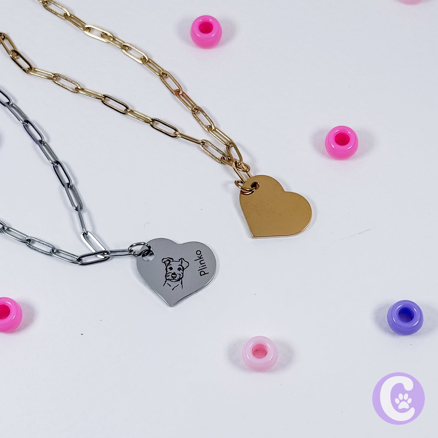Two heart-shaped pendant necklaces on a white background with small colorful beads around.