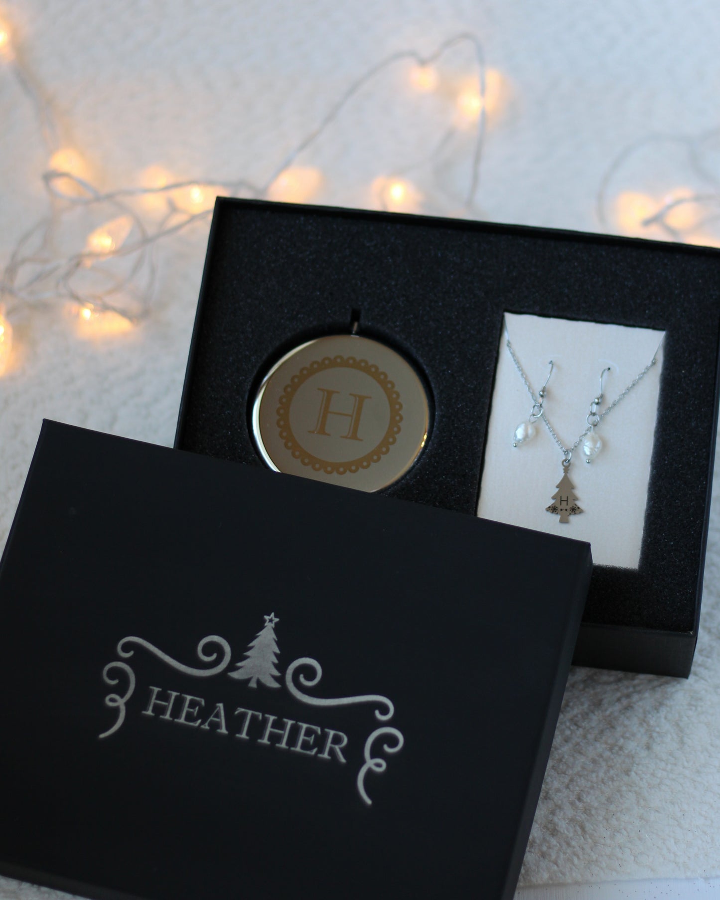 Jewelry set with pendant and necklace in a black box labeled 'Heather' on a soft background.