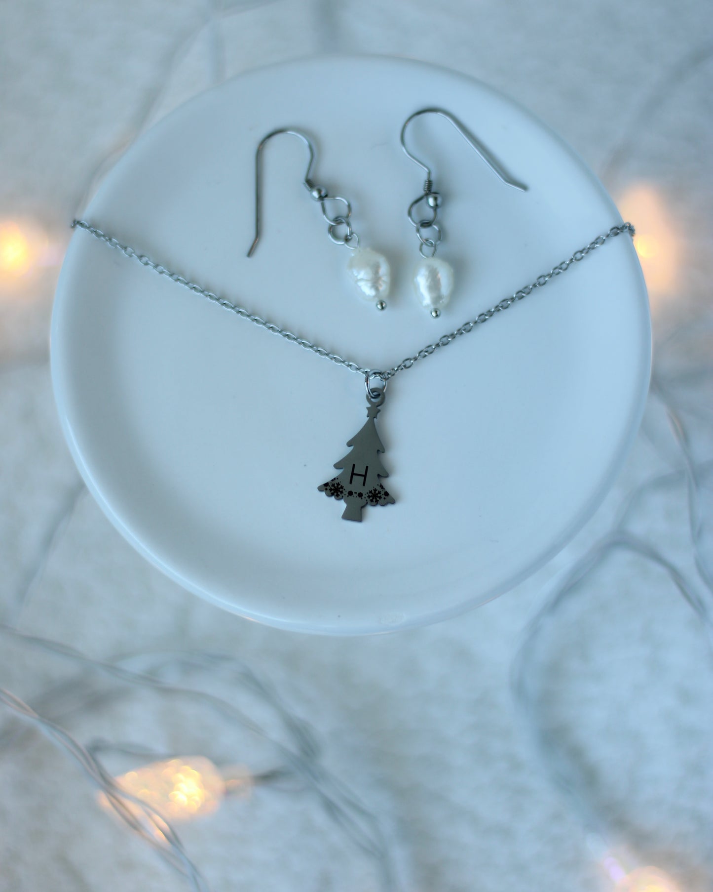 Silver necklace and earrings on a white dish with a blurred light background
