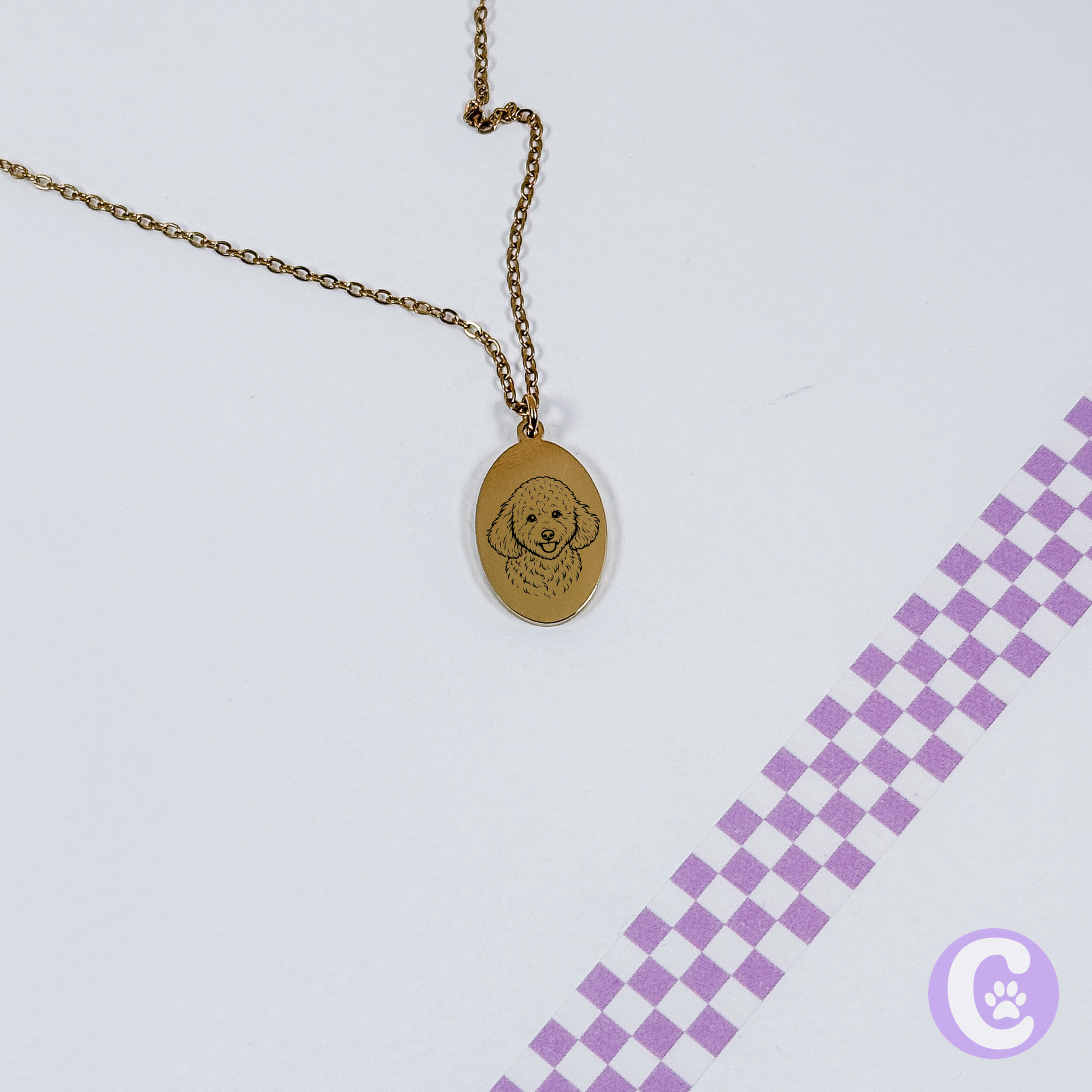 Gold necklace with pet line art pendant on a light purple background