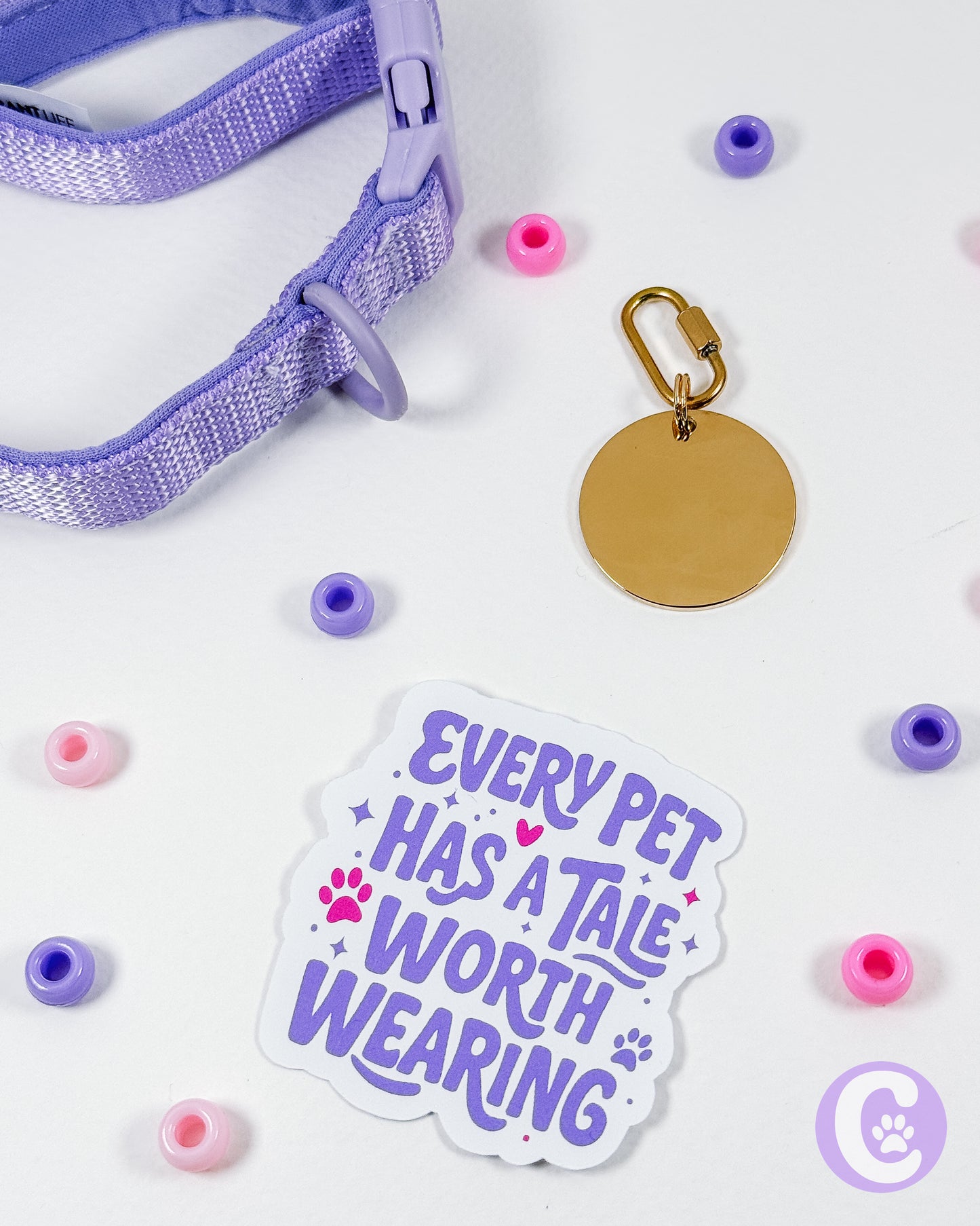 Purple pet collar with a gold tag and 'Every Pet Has a Tale Worth Wearing' sticker on a white background with colorful beads.