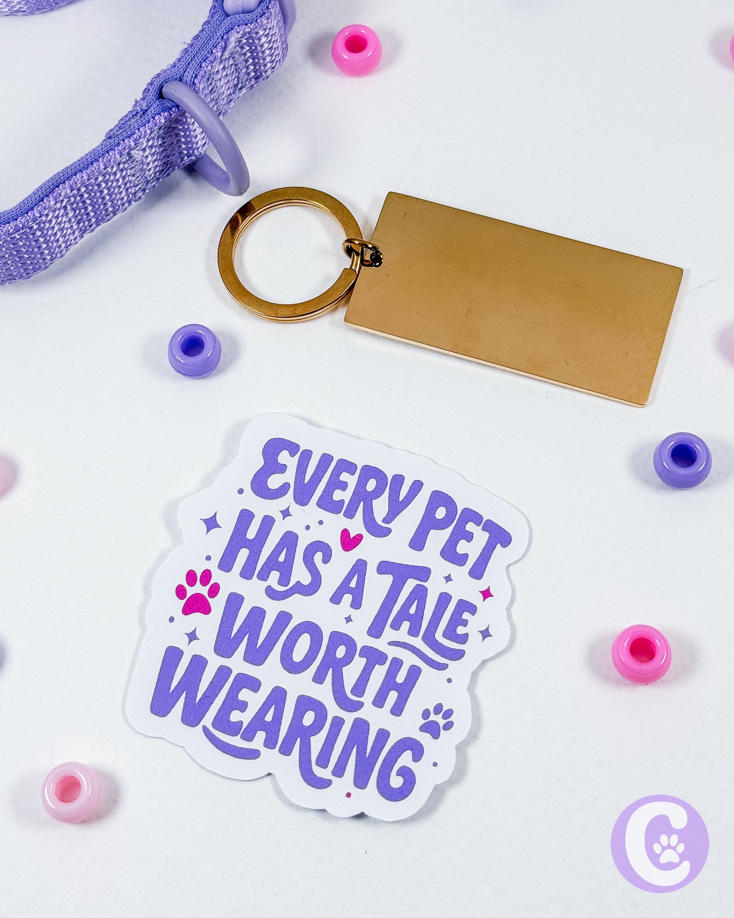 Sticker with 'Every pet has a tale worth wearing' text, keychain, and collar on a white background