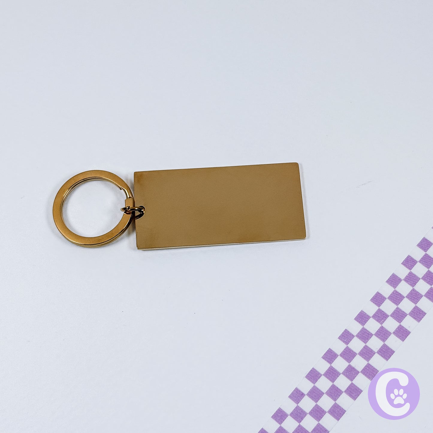 Gold keychain with a rectangular tag on a light gray background