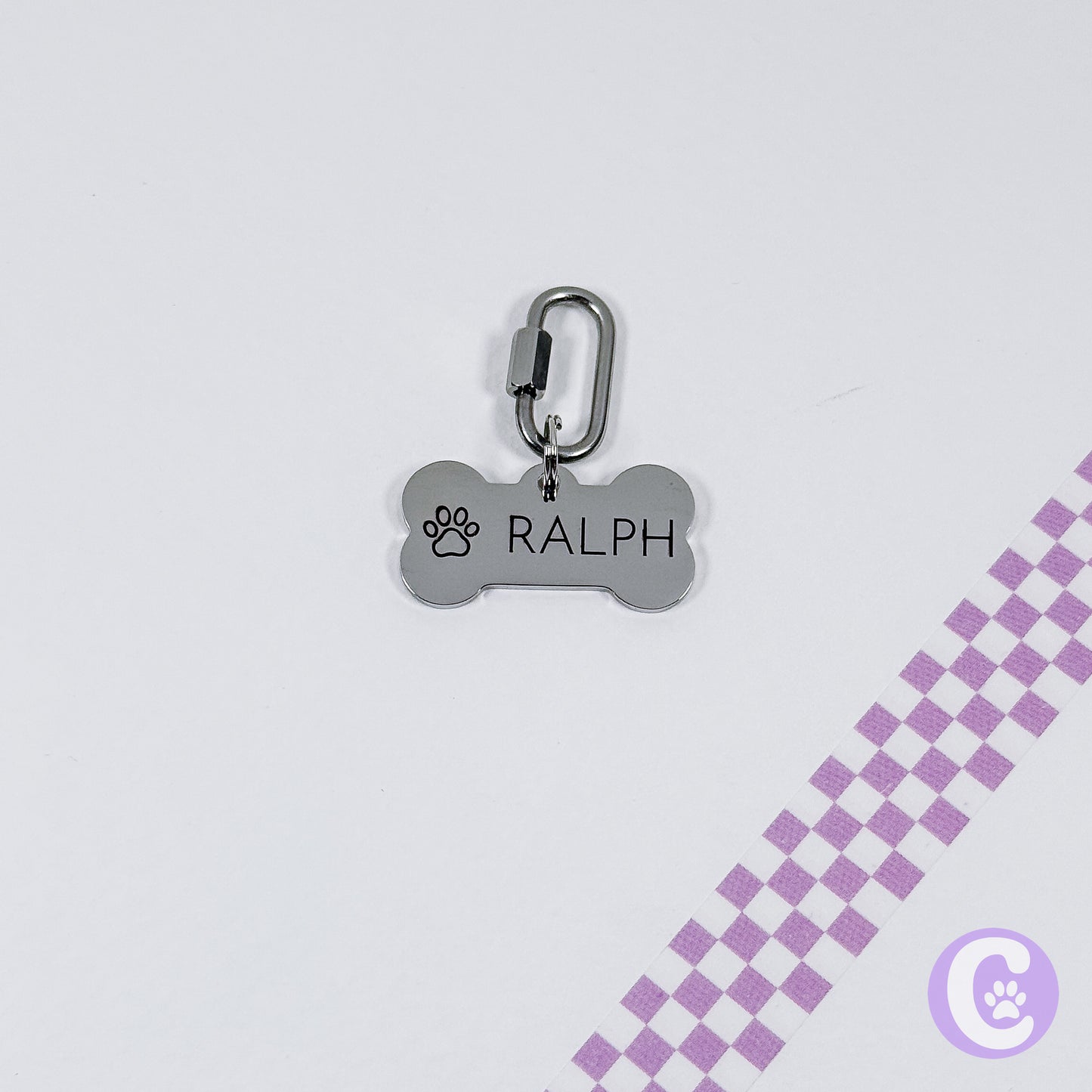 Dog tag with 'RALPH' engraved on a light gray background