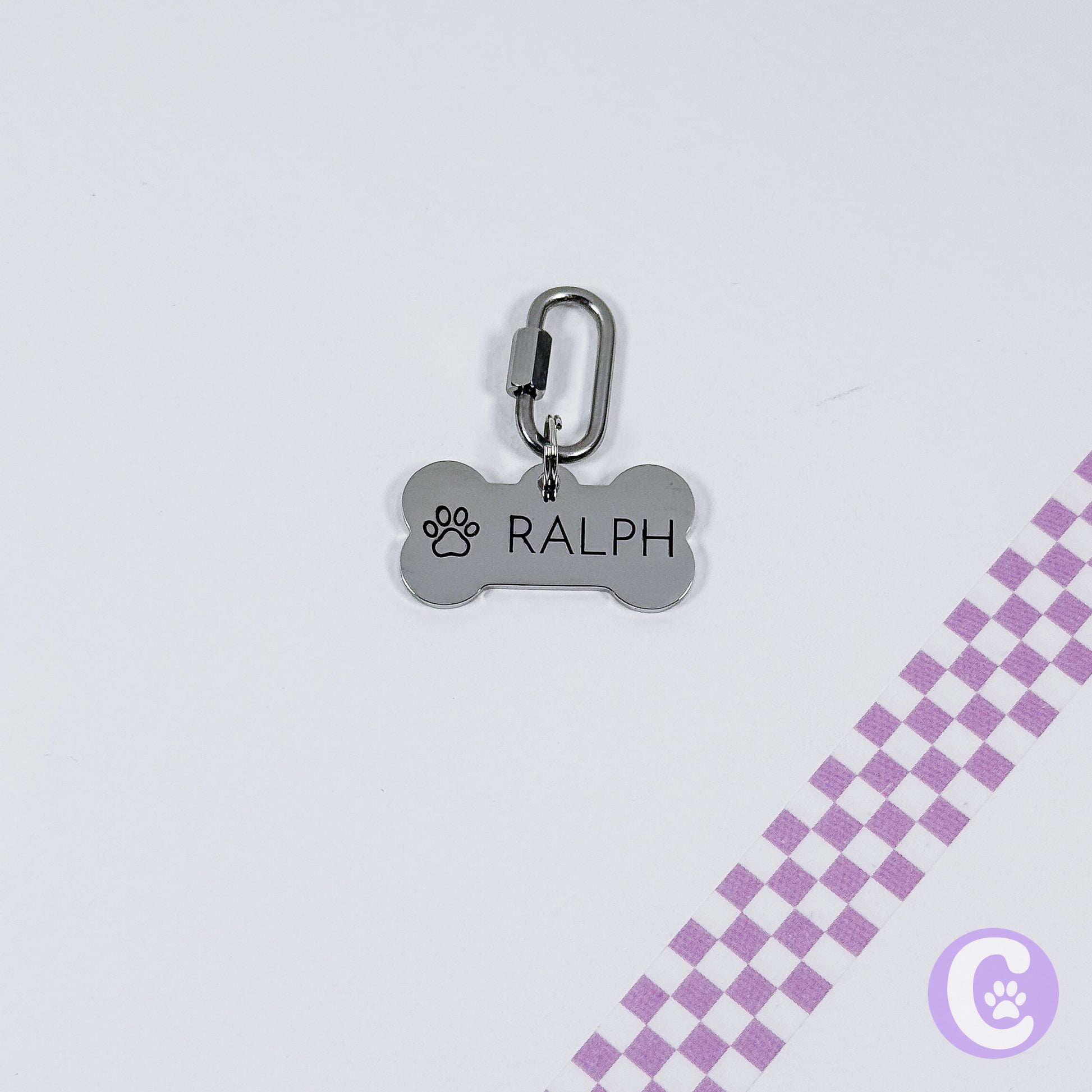 Dog tag with 'RALPH' engraved on a light gray background