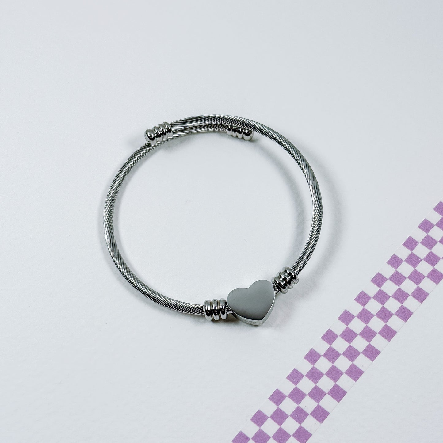 Silver bracelet with a heart charm on a light gray background