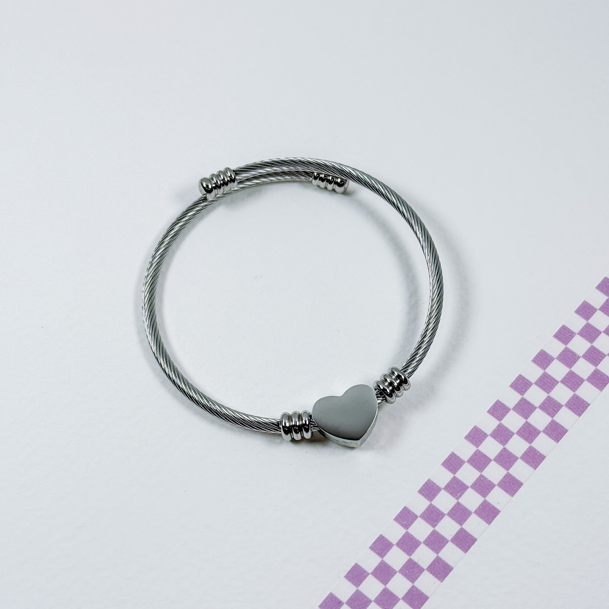 Silver bracelet with a heart charm on a light gray background
