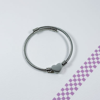 Silver bracelet with a heart charm on a light gray background