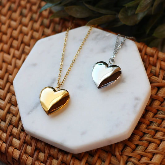 Gold and silver heart-shaped pendants on marble and woven surface