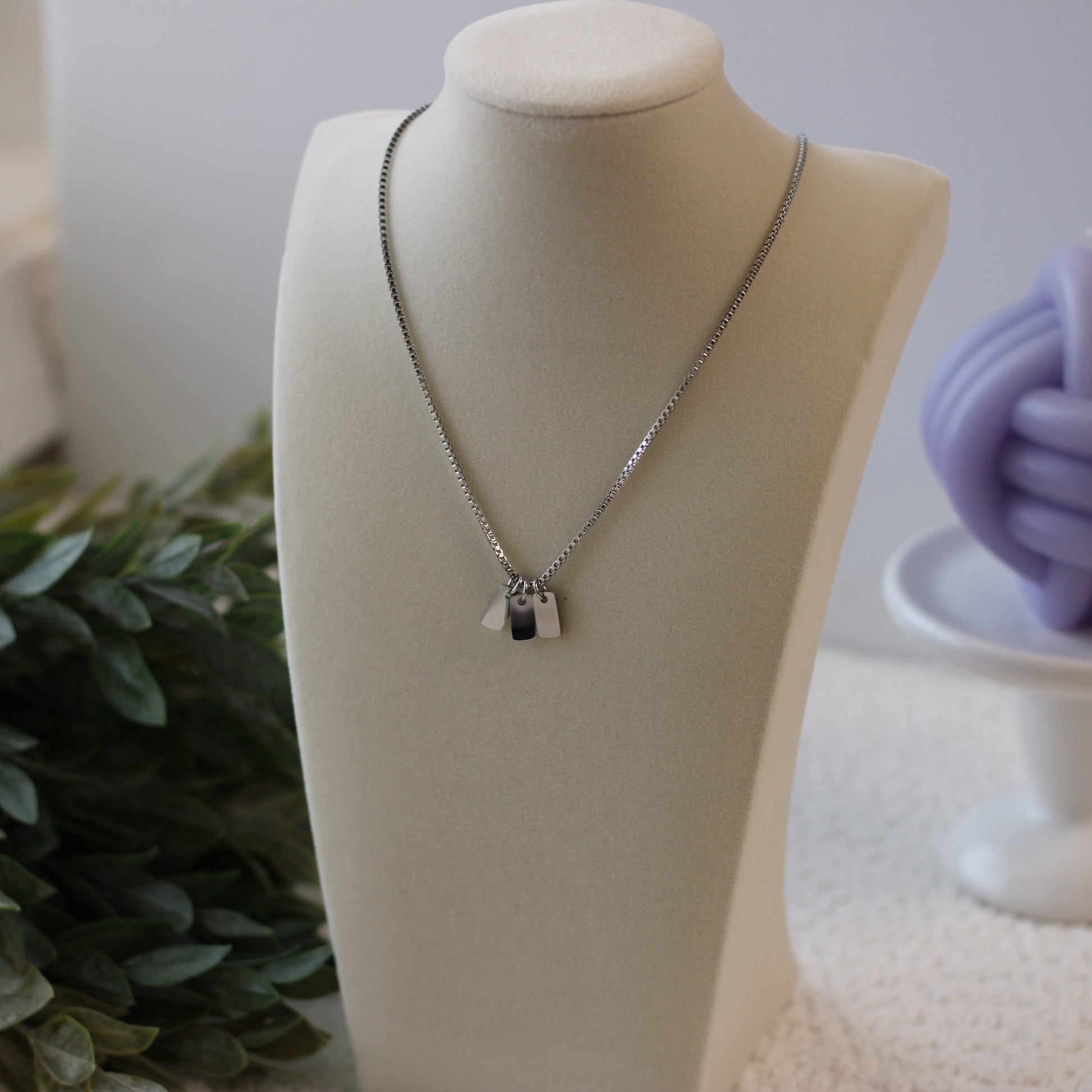 Silver necklace with a pendant on a mannequin bust against a neutral background