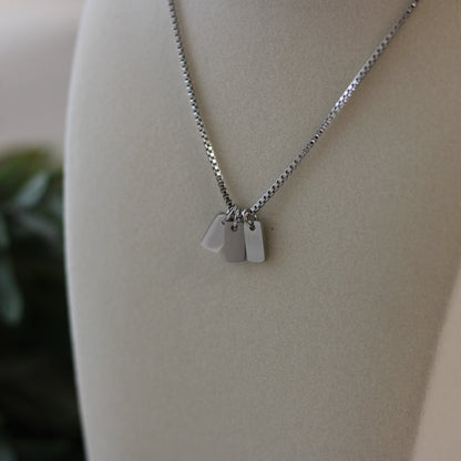 Silver necklace with three tags on a mannequin bust.